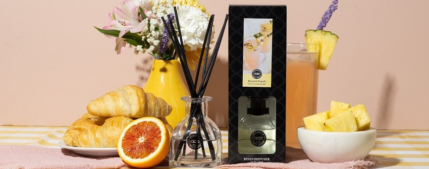Lyxig dDoftpinnar reed diffuser med persika och citrus från House Of Månsson, stylad med croissanter, apelsin, ananasdrink och blommor i ljus miljö
