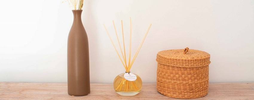 Cashmere Softness doftpinnar från Plantes & Parfums Provence placerade på en träyta tillsammans med en dekorativ vas och förvaringskorg. Elegant rumsdoft med doftstickor som skapar en varm och harmonisk atmosfär i hemmet hos House Of Månsson.